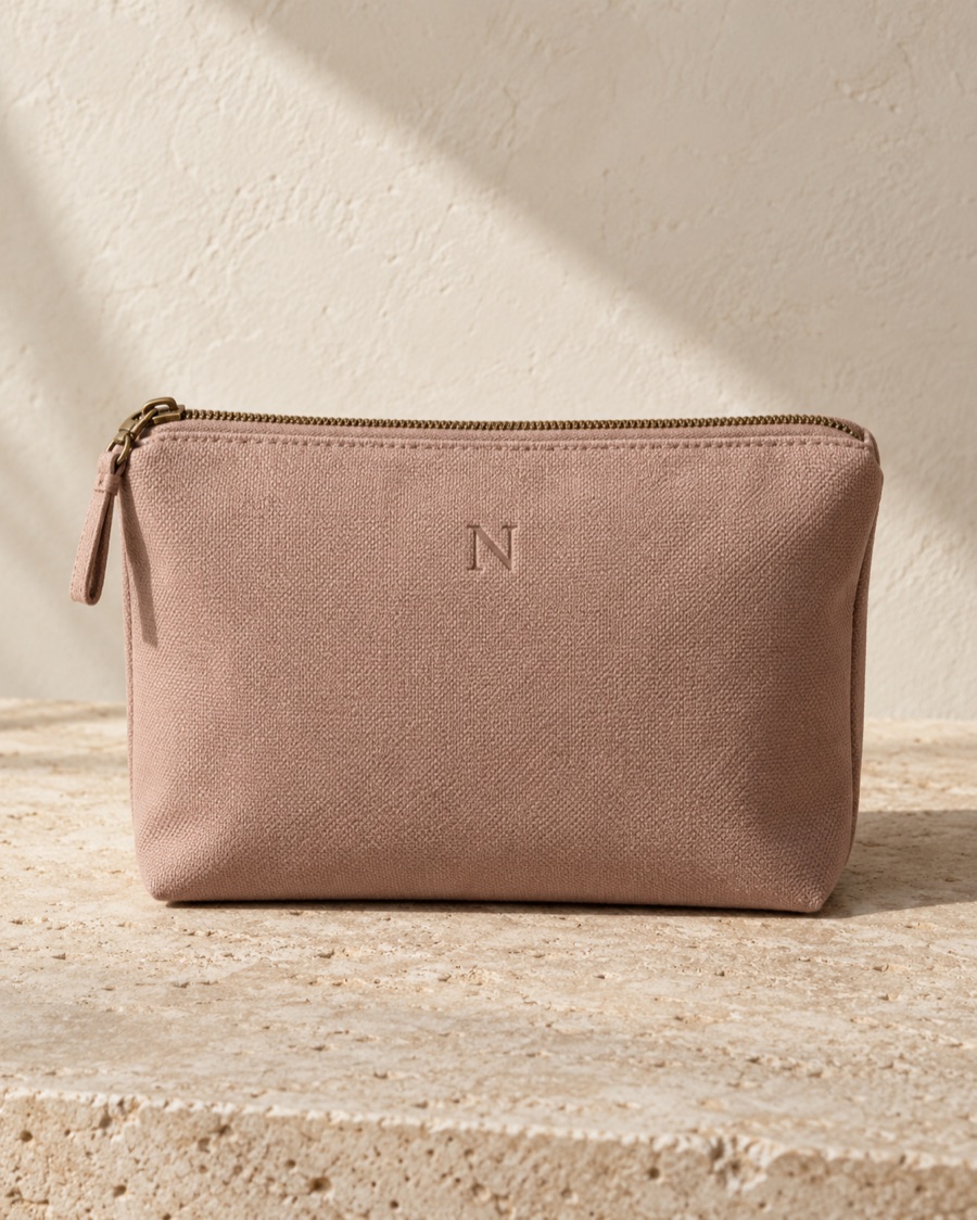 NOSTOS concept travel pouch in soft rose, photographed on warm limestone.